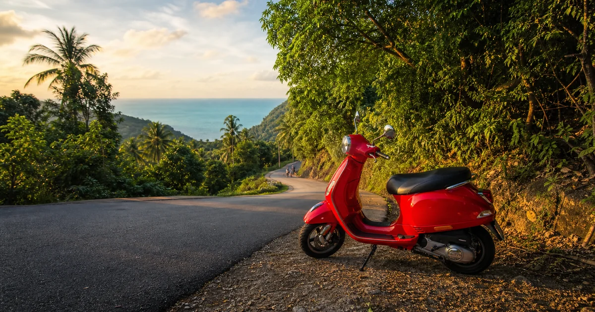 A scooter parked beside a turquoise sea bay on Phu Quoc Island, palm trees in the background and a sunny tropical sky