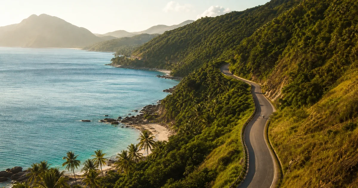 Motorbike rider on a coastal road in Phu Quoc with blue sea and green hills visible on both sides