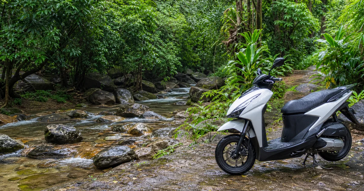 Rented scooter parked on a jungle path beside a clear stream near Suoi Tranh waterfall in Phu Quoc