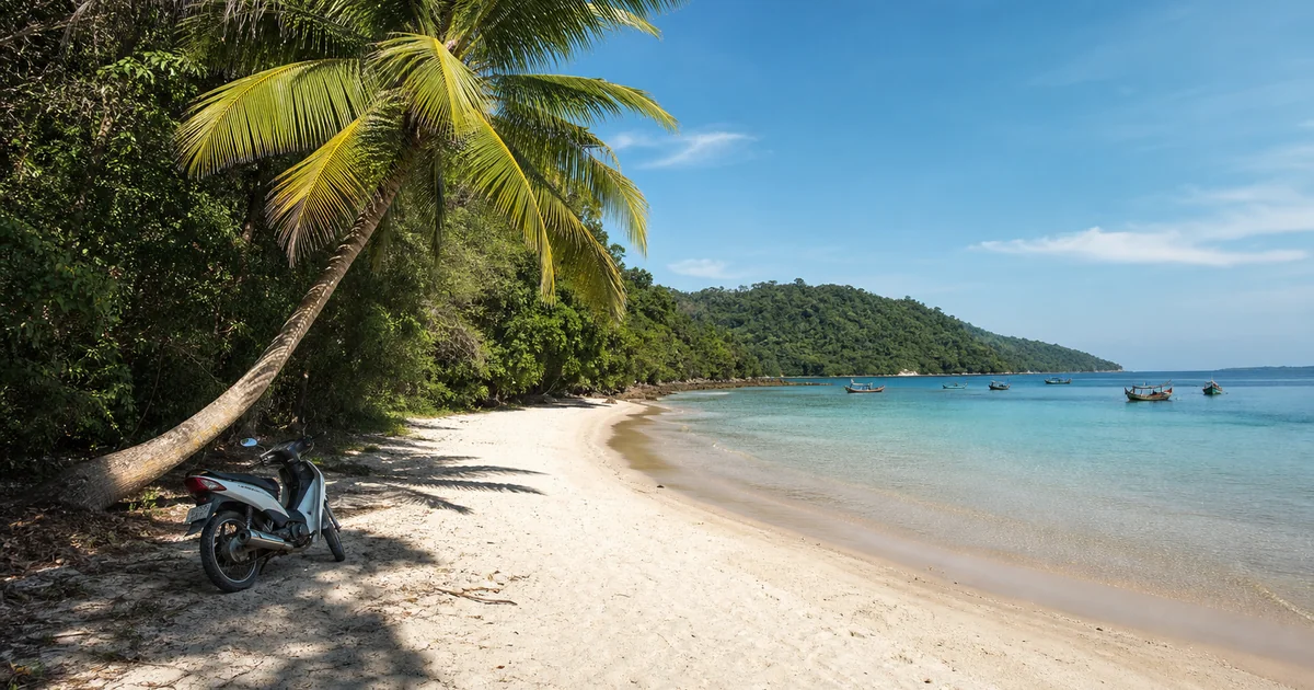 White sand and turquoise water at Sao Beach, Phu Quoc, with a motorbike parked at the tree line