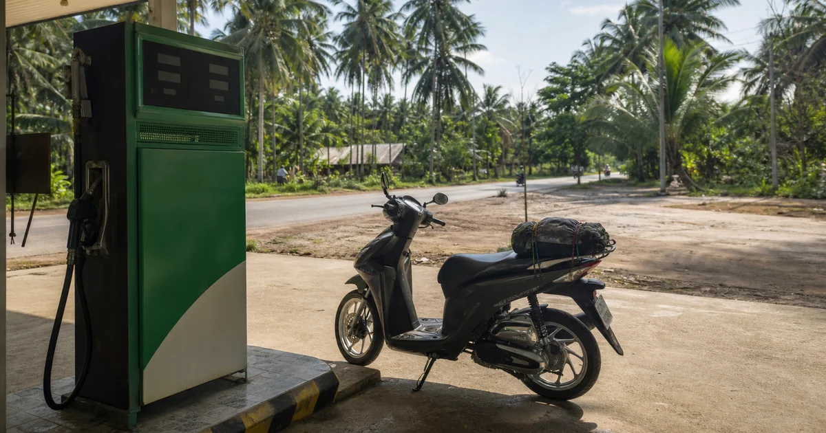 A scooter being refuelled at a petrol station on Phu Quoc Island, palm trees and tropical road in the background